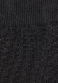 Crna pletena tkanina s rebrastom teksturom, koja ima glatku završnicu i ravnomjerno tkanje, pogodna za razne odjevne predmete.