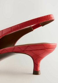 Rode slingback hoge hak schoen met een krokodillenstructuur, met een taps toelopende hak en een gladde bruine binnenkant.