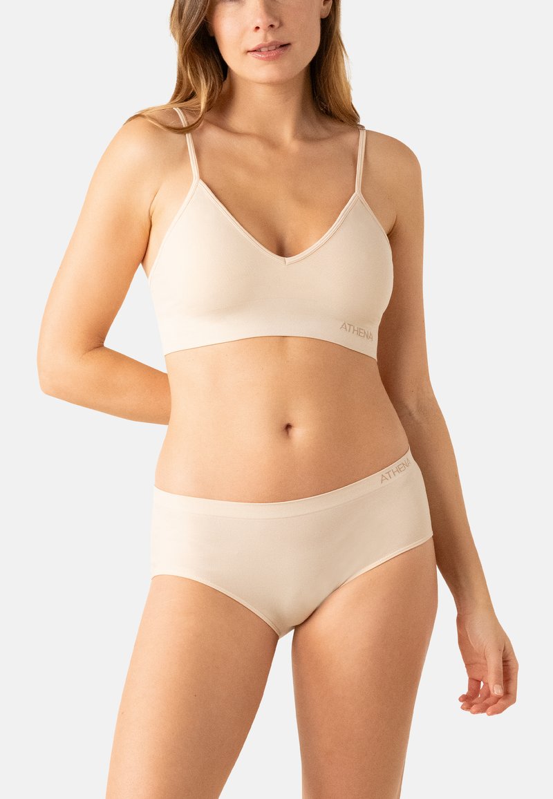 Bralette sans fil beige clair et culottes hipster assorties en tissu doux. Le bralette présente un décolleté en V et des bretelles ajustables ; logo sur la ceinture.