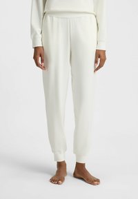 Pantalons de détente blancs en tissu doux, avec une coupe décontractée, une taille élastique et des bords fuselés aux chevilles.