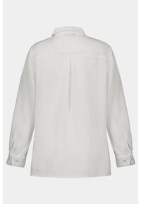 Camisa de lino blanca de manga larga, que presenta un puño abotonado, una yugo en la parte posterior y un pliegue centrado para un detalle adicional.