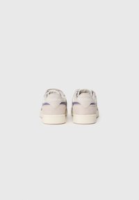 Sive sive tenisice s bijelom potplatom, s ljubičastim detaljem i utisnutim Reebok logotipom na peti. Jednostavan, klasičan dizajn.