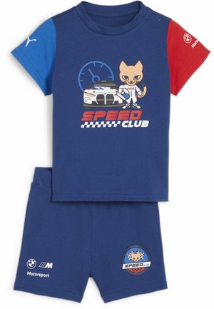 Børns blå todelte sæt med røde og blå ærmer, med en bil, tegneseriekat i racerdress, hastighedsmåler og teksten "Speed Club".