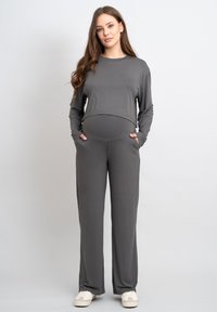 Grijze lange mouwen top met cropped zoom en bijpassende broek met zakken. Soepele, rekbare stof, relaxte pasvorm en zachte textuur.