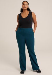 Pantalones de talle alto en color teal con un diseño de pierna recta, frente plano y bolsillos laterales, combinados con una blusa sin mangas negra.