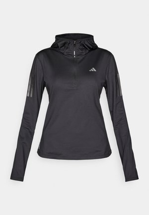 Black long-sleeve athletic hoodie with quarter zipper, textured fabric, adjustable hood, and reflective stripes on sleeves. Features logo on chest.