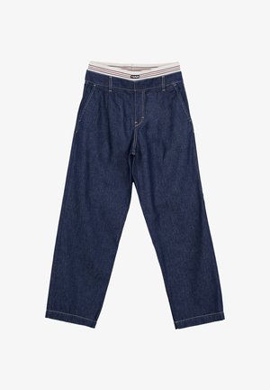 Ciemnoniebieskie spodnie dżinsowe o luźnych nogawkach z białym elastycznym pasem w czerwone i czarne paski oraz małym centralnym logo.