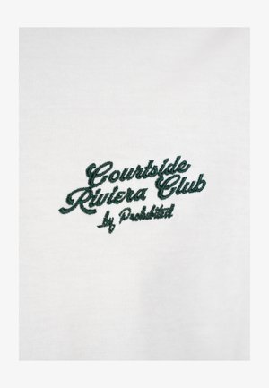 Texte brodé en vert « Courtside Riviera Club by Produktet » sur tissu blanc, probablement un vêtement.