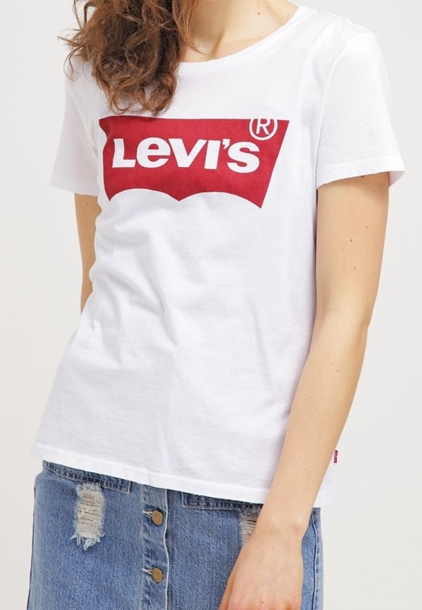 Vit bomull T-shirt med en framträdande röd Levi's-logotyp över bröstet. Matchas med en blå denimkjol med slitna detaljer.