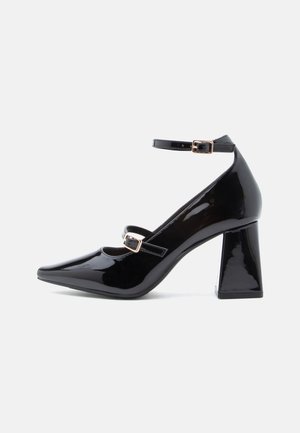 Black patent leather high heels with a pointed toe, two ankle straps, square block heel, and gold buckle accents. Smooth, glossy finish.