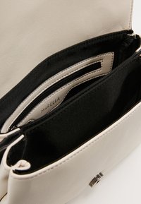 Borsa in pelle beige chiaro con più scomparti, fodera in tessuto nero, una cerniera in metallo e un'etichetta interna con "Marella."