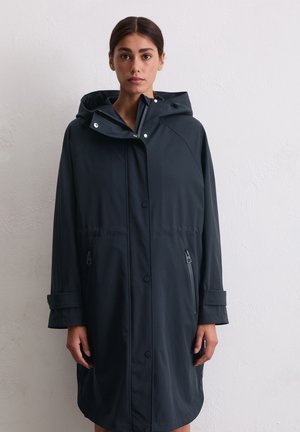 Donkerblauwe waterdichte jas met capuchon, voorzien van een ritssluiting aan de voorkant, drukknoopsluitingen en twee zijzakken met rits. Lange, licht oversized pasvorm.