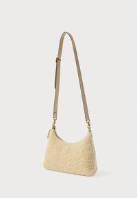 Hobo stila soma no krēmkrāsas mākslīgās kažokādas ar glaudītu brūnas ādas plecu siksnu un zelta aksesuāriem. Apaļa forma ar mīkstu tekstūru.