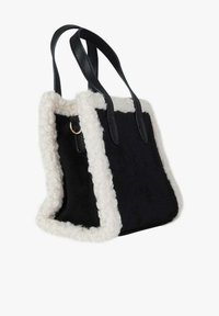 Borsa tote nera con rifiniture in tessuto peluche color crema, dotata di manici robusti in pelle nera e corpo in tessuto morbido. La base è di forma rettangolare.