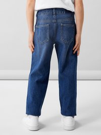 VAQUEROS de mezclilla en azul medio. Diseño de pierna ancha con una cinturilla elástica y dos bolsillos traseros. Llevados con zapatillas blancas.