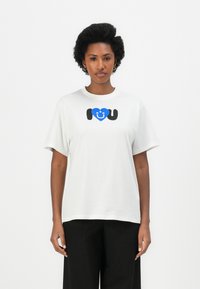 Witte katoenen T-shirt met korte mouwen, met een graphic print van een blauwe hart en de tekst "Ik ❤️ U" in zwart. Eenvoudig ontwerp met ronde hals.