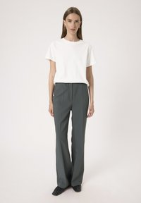 Bela kratka majica s kratkimi rokavi v kombinaciji z visokim pasom, širšimi temno sivo oblekami. Obleka se ponaša s čistim, minimalističnim dizajnom.