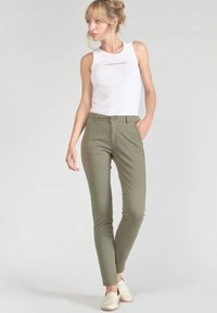 Olijfgroene, slim-fit chino's van een katoenmix, met een knoopsluiting en voorkruiszakken, gecombineerd met een witte mouwloze top.