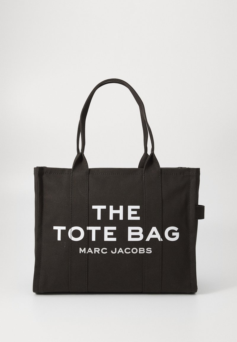 Crna platnena torba s bijelim tiskanim tekstom "THE TOTE BAG MARC JACOBS." Ima dva čvrsta ručka i pravokutni oblik.