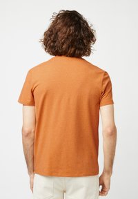 Korte mouwen, ronde hals t-shirt in een gestructureerde verbrande sinaasappelstof, met een rechte zoom en minimale naden op de achterkant.