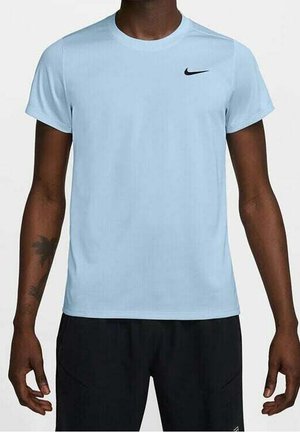 Mand iført lyseblå Nike kortærmet t-shirt og sorte shorts, stående med armene afslappet ved siden.