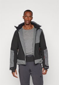 Chaqueta de invierno negra y gris con cuello alto, cierre frontal con cremallera, dos bolsillos laterales, puños ajustables y un diseño entallado.