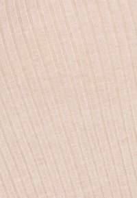 Světlý béžový žebrovaný materiál s hladkým povrchem, s úzkými vertikálními pruhy. Materiál vypadá měkký a elastický.