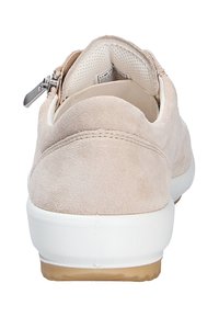 Béžová semišová bota s bílou gumovou podrážkou a hnědými akcenty. Má zipový uzávěr na patě a hladké vnitřní podšití.