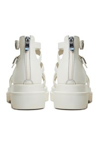 White leather sandals with an adjustable ankle strap, silver zippers at the back, and a thick, textured sole for grip.