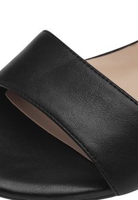 Schwarze Rutsch-Sandale mit einem breiten strukturierten Lederriemen, offenem Zehenbereich und einem neutralen Fußbett. Glatter Schuhboden für Komfort.