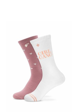 Deux chaussettes mi-mollet, une rose poudré avec de petits cœurs blancs, une blanche avec un texte pêche "GIRL GANG" et des rayures assorties sur le bout du pied.