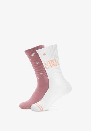 Deux chaussettes mi-mollet, une rose poudré avec de petits cœurs blancs, une blanche avec un texte pêche "GIRL GANG" et des rayures assorties sur le bout du pied.