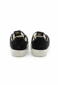 Sneakers in suede nero con una parte superiore testurizzata, foderati in pelo bianco e con una suola bianca a contrasto. I dettagli posteriori includono un'etichetta con il logo.