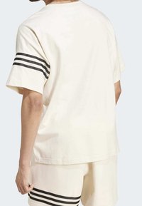 Kortärmad t-shirt i gräddvit bomull med svarta randiga detaljer på ärmarna, avslappnad passform och enfärgad bakdesign.