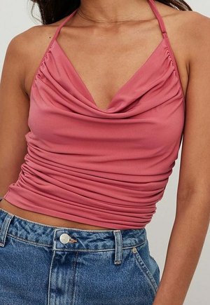 Roze haltertop met een gedrapeerde halslijn, gerimpelde textuur en verstelbare bandjes, gecombineerd met blauwe high-waisted denimshorts.
