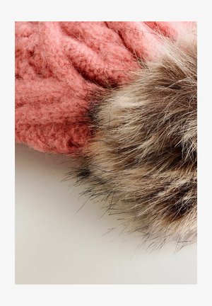 Pink knitted fabric with textured pattern next to a soft, fluffy, multicolored fur pom-pom on a light surface.