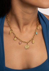 Collana in tono dorato con catena, caratterizzata da vari ciondoli: un sole, una stella, una goccia, un triangolo e un ovale, in diversi colori e texture.
