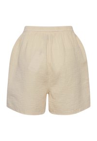 Pantaloncini in cotone beige con texture, dotati di vita elastica e tasche laterali, mostrati su uno sfondo bianco semplice.
