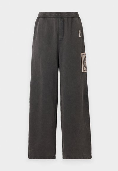 Bredde bukser i mørkegrå stof, med et dekorativt patch på frontlommen og en elastisk talje for komfort.