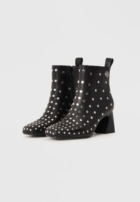 Black leather ankle boots with silver metal studs, pointed toe, and block heel. Features a side zipper and pull tabs for easy wear.