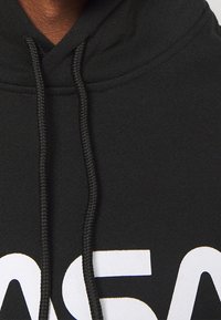 Schwarzer Hoodie aus weichem Material mit einem auffälligen weißen "NASA"-Logo. Mit verstellbarem Kapuzenzug und gerippten Bündchen.