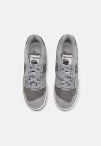 Paire de baskets New Balance 550 grises avec lacets, vue de dessus sur fond blanc.