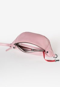 Roze leren tas met een ronde vorm, bovenaan met ritssluiting, een rode accentriem en een binnenvak met een subtiel patroon.