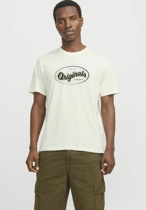 Lichtbeige katoenen t-shirt met korte mouwen en een ronde halslijn, voorzien van een zwart "Originals" logo in een ovale omtrek aan de voorkant.