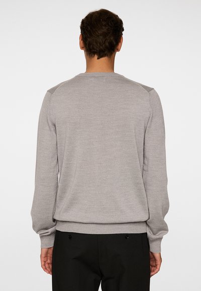 Harmaa neulottu neulepusero pitkillä hihoilla, pyöreällä kaula-aukolla, teksturoidusta kankaasta ja ribbaustetuilla hiharesoreilla. Ei näkyviä kuvioita tai varusteita.