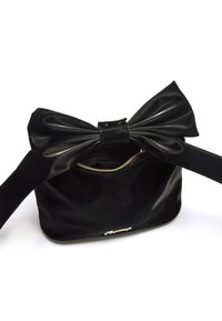 Borsa nera lucida con un grande fiocco sulla parte superiore, tasca frontale con zip e una texture liscia. Presenta un'accessorio con logo dorato.