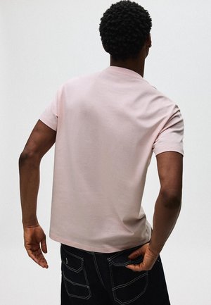 Ljusrosa t-shirt med korta ärmar i mjukt tyg, har en rund halsringning och enfärgad design. Kombineras med mörka jeans i denim.