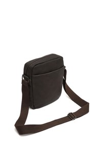 Brun læder crossbody taske med en glat tekstur, rektangulær form, lynlåslukning øverst og en robust stofrem. Detaljeret lomme foran.
