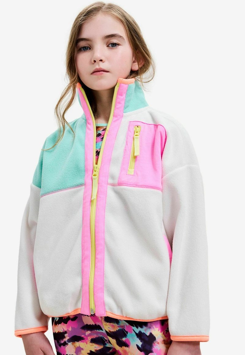 Veste en polaire colorée présentant des panneaux turquoise, rose et blanc, avec une fermeture éclair intégrale, un col montant et des accents de fermeture éclair jaunes contrastants.