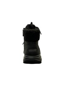 Botte noire imperméable avec un col en fausse fourrure, talon rond et logo sur le côté. Dispose d'une fermeture éclair et d'une semelle extérieure texturée.